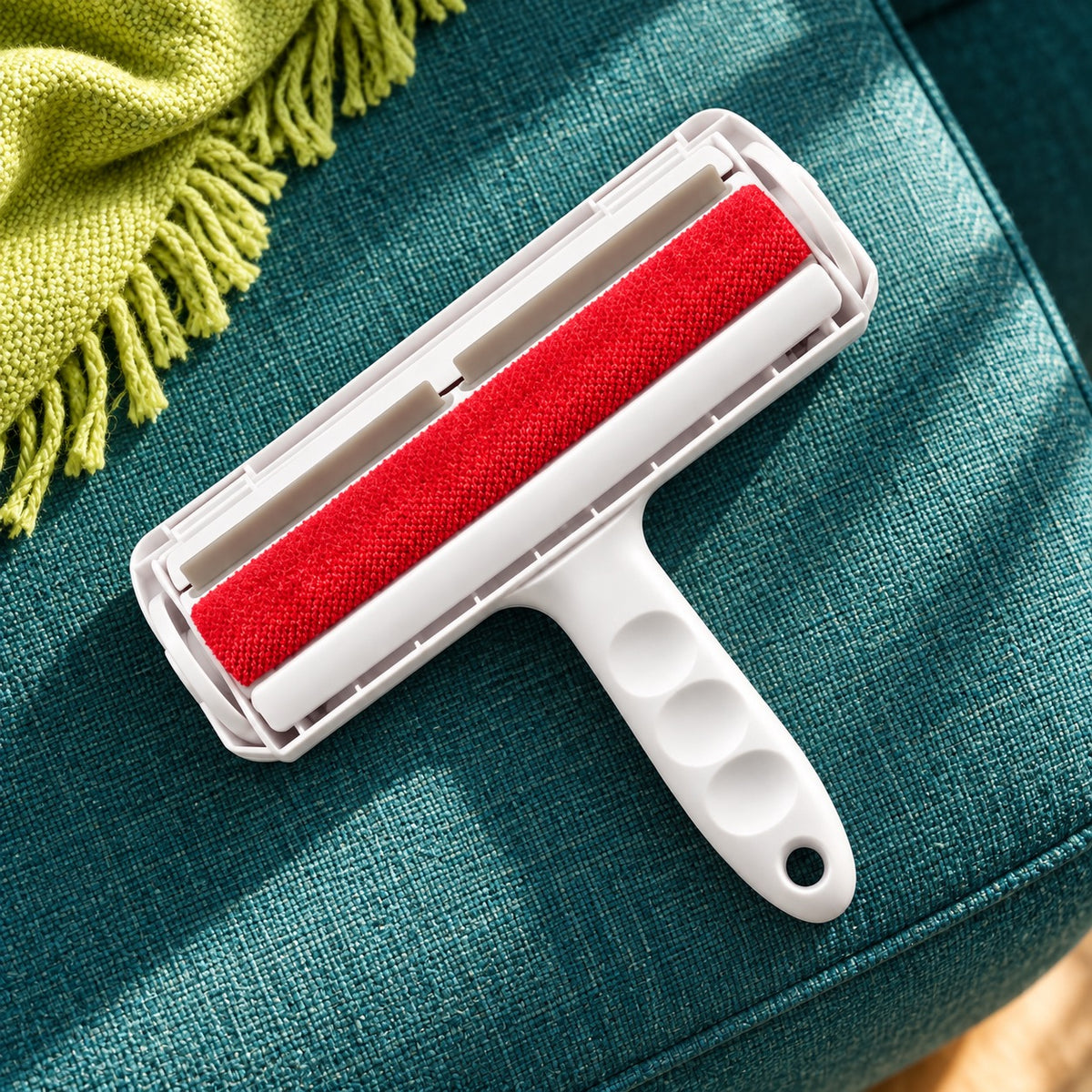 White and red FurSwift reusable pet hair roller on a teal sofa beside a lime throw